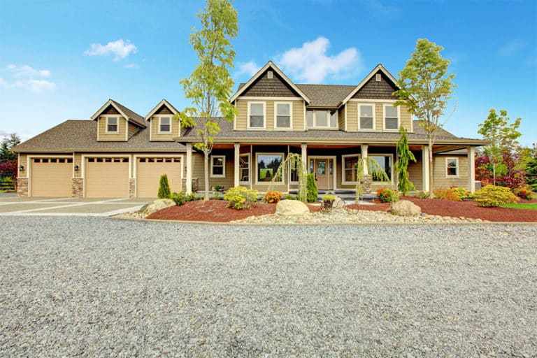 Large farm country house with gravel driveway and green landscape.