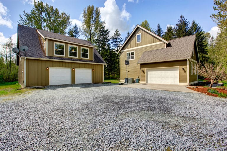 Countryside house exterior with garage. View of entrance and gravel driveway